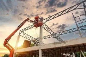 Worker on a boom lift platform beside a steel structure under construction