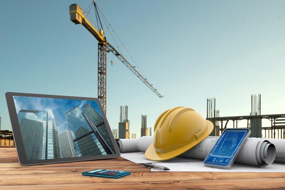 Construction plans and hard hat with a tower crane in the background