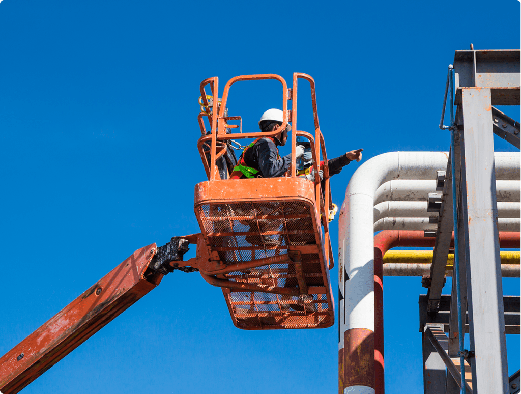 a man on a cherry picker working on a pipe.