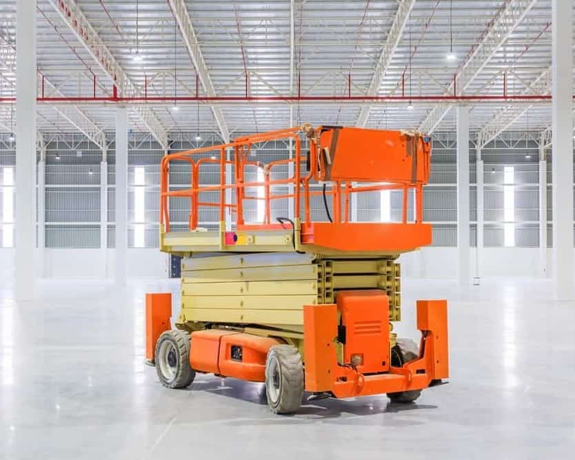 an orange and yellow scissor in a warehouse.