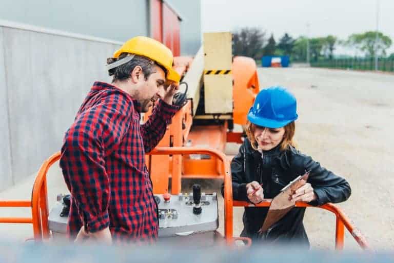 A man and woman wearing hard hats are participating in AWP training.