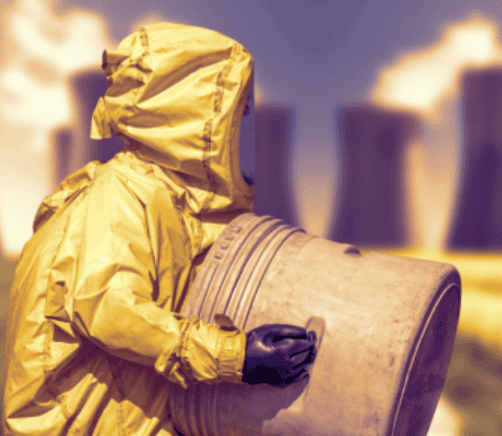 Person in a yellow hazmat suit and black gloves handling a large metal barrel with industrial cooling towers in the background.